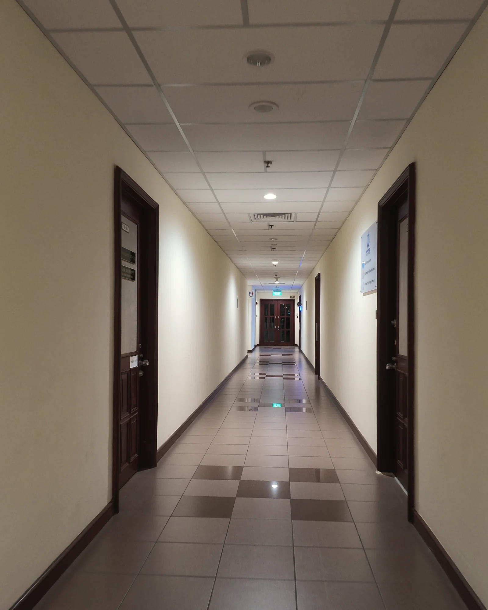 A long, symmetrical level 3 corridor at Balmoral Plaza with cream walls and a chequered tiled floor